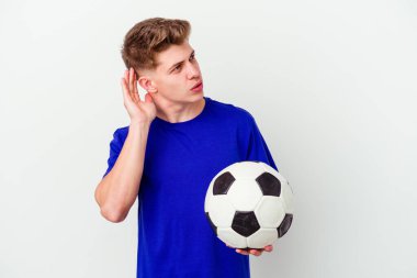 Futbol oynayan beyaz bir genç arka planda izole edilmiş bir şekilde bir dedikoduyu dinlemeye çalışıyor..
