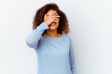 Beyaz arka planda izole edilmiş genç bir Afrikalı Amerikalı kadın elleriyle gözlerini kapatıyor, gülümseyerek büyük bir sürpriz bekliyor..