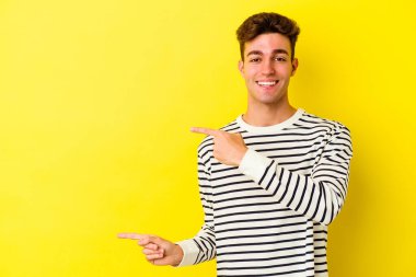 Sarı arka planda izole edilmiş genç beyaz adam işaret fişekleriyle işaret ederek heyecanlanıyor..