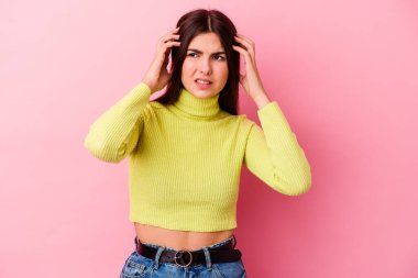 Pembe arka planda izole edilmiş genç beyaz bir kadın parmaklarıyla kulaklarını kapatıyor, gürültülü bir ortam yüzünden stresli ve çaresiz..