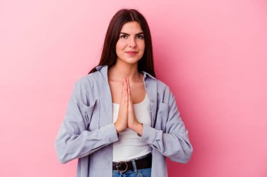 Pembe arka planda izole edilmiş genç beyaz kadın dua ediyor, bağlılık gösteriyor, dindar biri ilahi ilham arıyor..