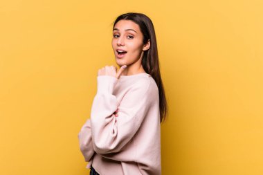 Sarı arka planda izole edilmiş genç Hintli kadın başparmak uzakta, gülüyor ve kaygısız.