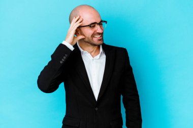 Genç, beyaz, kel bir adam mavi arka planda izole edilmiş neşeli bir şekilde gülüyor. Mutluluk kavramı.