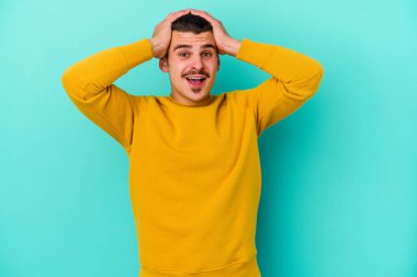 Genç beyaz adam mavi arka planda izole edilmiş bağırıyor, çok heyecanlı, tutkulu, bir şeyden memnun..