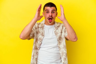 Sarı arka planda izole edilmiş genç beyaz adam şaşırdı ve şok oldu..