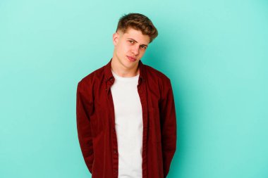 Kafkasyalı genç adam mavi arka planda izole edilmiş üzgün, ciddi yüzlü, mutsuz ve hoşnutsuz..