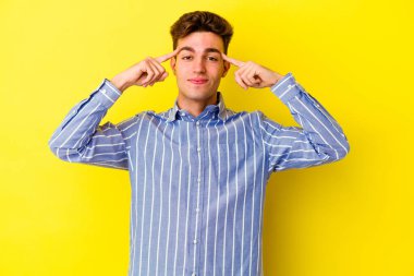 Sarı arka planda izole edilmiş genç beyaz adam bir göreve odaklanmış, işaret parmaklarını işaret ediyor..