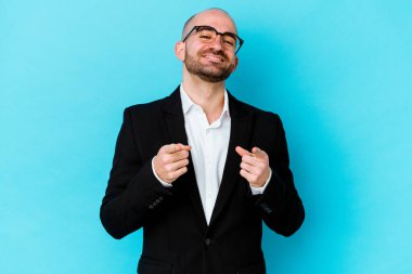 Genç beyaz tenli kel adam mavi arka planda izole edildi. Neşeli gülümsemeler ön tarafı gösteriyor..