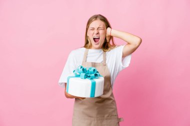 Genç Rus fırıncı kadın lezzetli bir pasta tutuyor kulakları kulaklarıyla örtüyor yüksek sesle duymamaya çalışıyor..