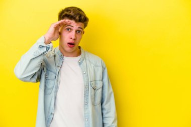 Sarı arka planda izole edilmiş genç beyaz adam yüksek sesle bağırıyor, gözleri açık ve elleri gergin tutuyor..