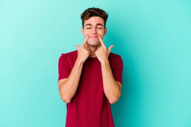 Kafkasyalı genç adam mavi arka planda izole edilmiş iki seçenek arasında şüphe duyuyor.