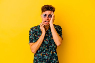 Hawaii gömleği giyen genç beyaz adam sarı arka planda izole edilmiş sızlanıyor ve ağlıyordu..