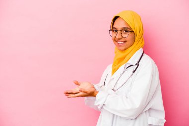 Pembe arka planda izole edilmiş genç bir doktor kadın. Elinde palmiye ağacında bir kopyası var..