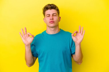 Sarı arka planda izole edilmiş genç beyaz adam sıkı çalışma gününden sonra rahatlıyor. Yoga yapıyor..