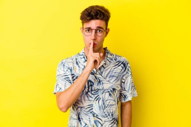Sarı arka planda izole edilmiş genç beyaz bir adam ya sır saklıyor ya da sessizlik istiyor..