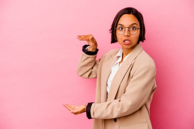 Pembe arka planda izole edilmiş genç iş kadını elleri arasında bir kopya alanı tutarken şok ve hayret içinde..