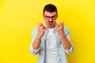 Sarı arka planda izole edilmiş genç beyaz adam gergin ellerle çığlık atıyor..