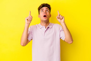 Sarı arka planda izole edilmiş beyaz bir adam ağzı açık bir şekilde üst tarafı işaret ediyor..