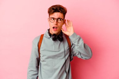 Pembe arka planda izole edilmiş genç bir öğrenci bir dedikoduyu dinlemeye çalışıyor..