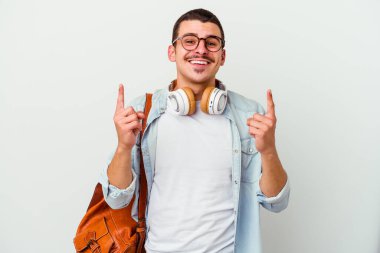 Beyaz arka planda izole edilmiş müzik dinleyen beyaz tenli genç bir öğrenci iki ön parmağıyla boş bir alan gösterdiğini gösteriyor..