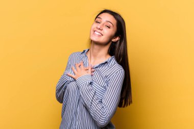 Sarı arka planda izole edilmiş genç Hintli kadın, dost bir ifadeye sahip, avuçlarını göğsüne bastırıyor. Aşk konsepti.