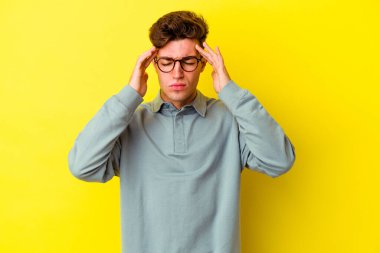 Sarı arka planda izole edilmiş genç beyaz adam tapınaklara dokunuyor ve baş ağrısı çekiyor..