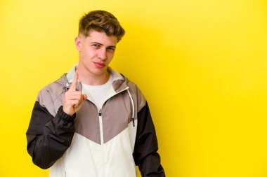 Sarı arka planda izole genç beyaz adam parmak ile bir numara gösteriyor.