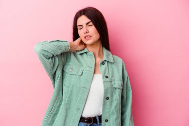 Pembe arka planda izole edilmiş genç beyaz kadın stresten dolayı boynu ağrıyor, masaj yapıyor ve elle dokunuyor..