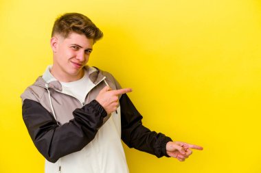 Sarı arka planda izole edilmiş genç beyaz adam işaret parmağıyla fotokopi alanını işaret ederek heyecan ve arzusunu ifade ediyor..