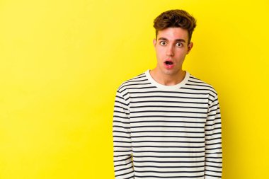 Sarı arka planda izole edilmiş genç beyaz adam gördüğü bir şey yüzünden şoka uğruyor..