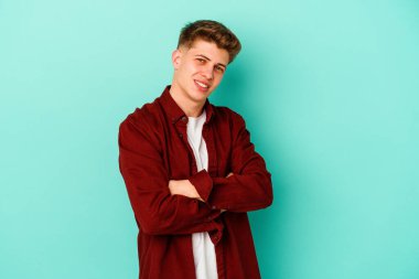 Kafkasyalı genç adam mavi arka planda izole edilmiş gülüyor ve eğleniyor..