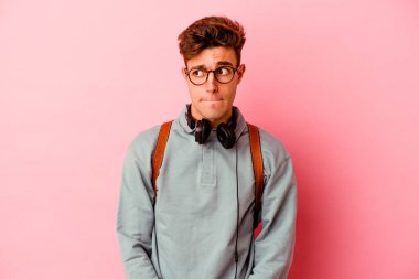 Pembe arka planda izole edilmiş genç bir öğrenci kafası karışmış, şüpheli ve güvensiz hissediyor..