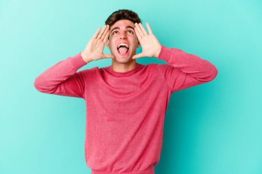 Mavi arka planda izole edilmiş beyaz bir adam heyecanlı bir şekilde bağırıyor..