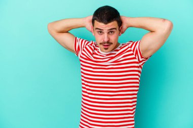 Genç beyaz adam mavi arka planda izole edilmiş bağırıyor, çok heyecanlı, tutkulu, bir şeyden memnun..