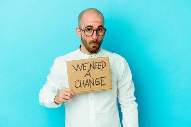 Kafkasyalı kel bir adam elinde mor arka planda izole edilmiş bir pankart omuz silkiyor ve kafası karışmış gözlere ihtiyacımız var..