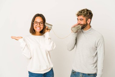 Latin kökenli genç arkadaşlar, teneke kutu sisteminden konuşuyorlar. Avuç içlerindeki fotokopi alanlarını gösteriyorlar ve başka bir eli belinde tutuyorlar..