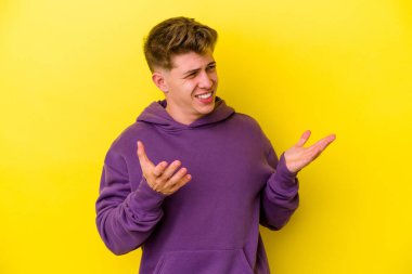 Sarı arka planda izole edilmiş genç beyaz bir adam neşeli bir şekilde gülüyor. Mutluluk kavramı.