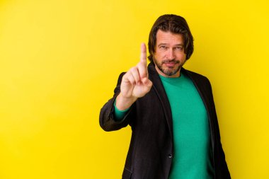 Sarı arka planda izole edilmiş orta yaşlı beyaz bir adam bir numarayı parmağıyla gösteriyor..