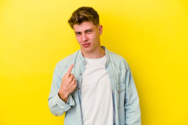 Sarı arka planda izole edilmiş genç beyaz adam sanki seni davet ediyormuş gibi seni işaret ediyor..