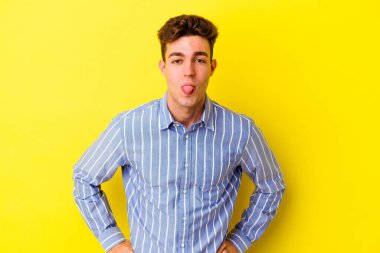 Sarı arka planda izole edilmiş beyaz bir genç. Komik ve dost canlısı bir dil uzatıyor..