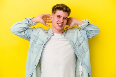 Sarı arka planda izole edilmiş, kollarını uzatan, rahat bir pozisyonda genç beyaz bir adam..