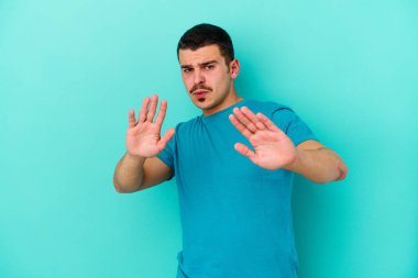 Mavi arka planda izole edilmiş genç beyaz adam tiksinti belirtisi gösteren birini reddediyor..