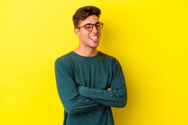 Sarı arka planda izole edilmiş beyaz bir genç. Komik ve dost canlısı bir dil uzatıyor..