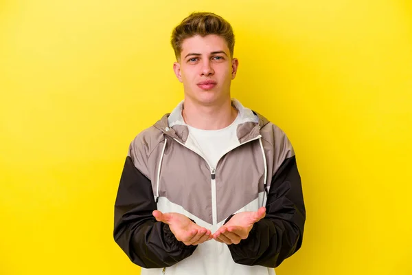 Νεαρός Καυκάσιος Άνδρας Απομονωμένος Κίτρινο Φόντο Κρατώντας Κάτι Παλάμες Προσφέροντας — Φωτογραφία Αρχείου