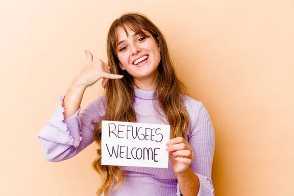 Young caucasian woman holding a Refugees welcome placard isolated showing a mobile phone call gesture with fingers.