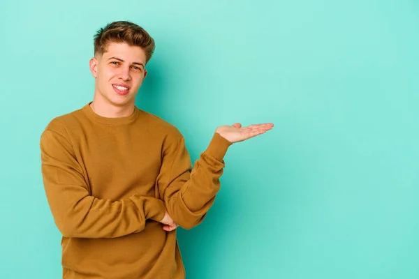 Joven Hombre Caucásico Aislado Sobre Fondo Azul Mostrando Espacio Copia —  Fotos de Stock