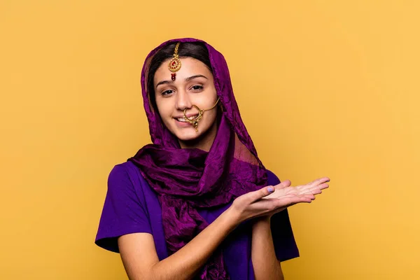 黄色の背景に隔離された伝統的なサリーを身に着けている若いインド人女性は ヤシの上にコピースペースを保持 — ストック写真