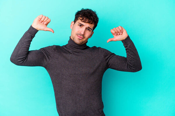 Молодой кавказский человек на голубом фоне чувствует себя гордым и уверенным в себе, пример для подражания.