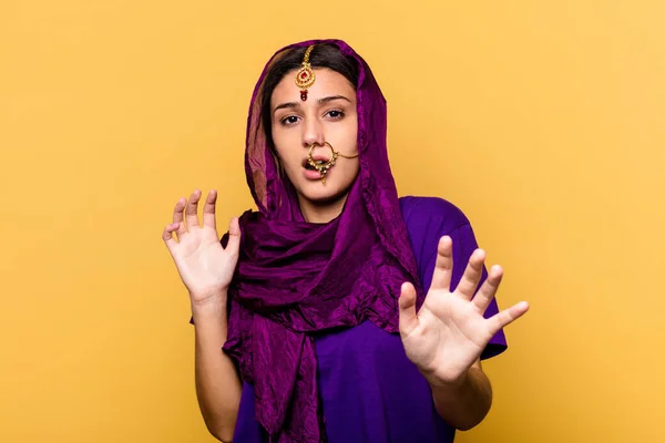 黄色の背景に隔離された伝統的なサリーを身に着けている若いインド人女性は 差し迫った危険性のためにショックを受けています — ストック写真