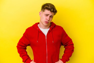 Sarı arka planda izole edilmiş genç beyaz adam yanakları patlatır, yorgun bir ifadeye sahiptir. Yüz ifadesi kavramı.